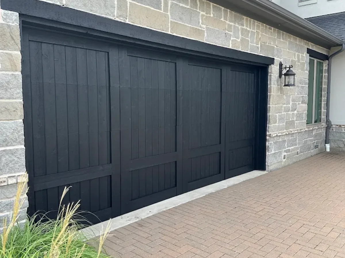 Black wood panel garage door on a stone exterior home