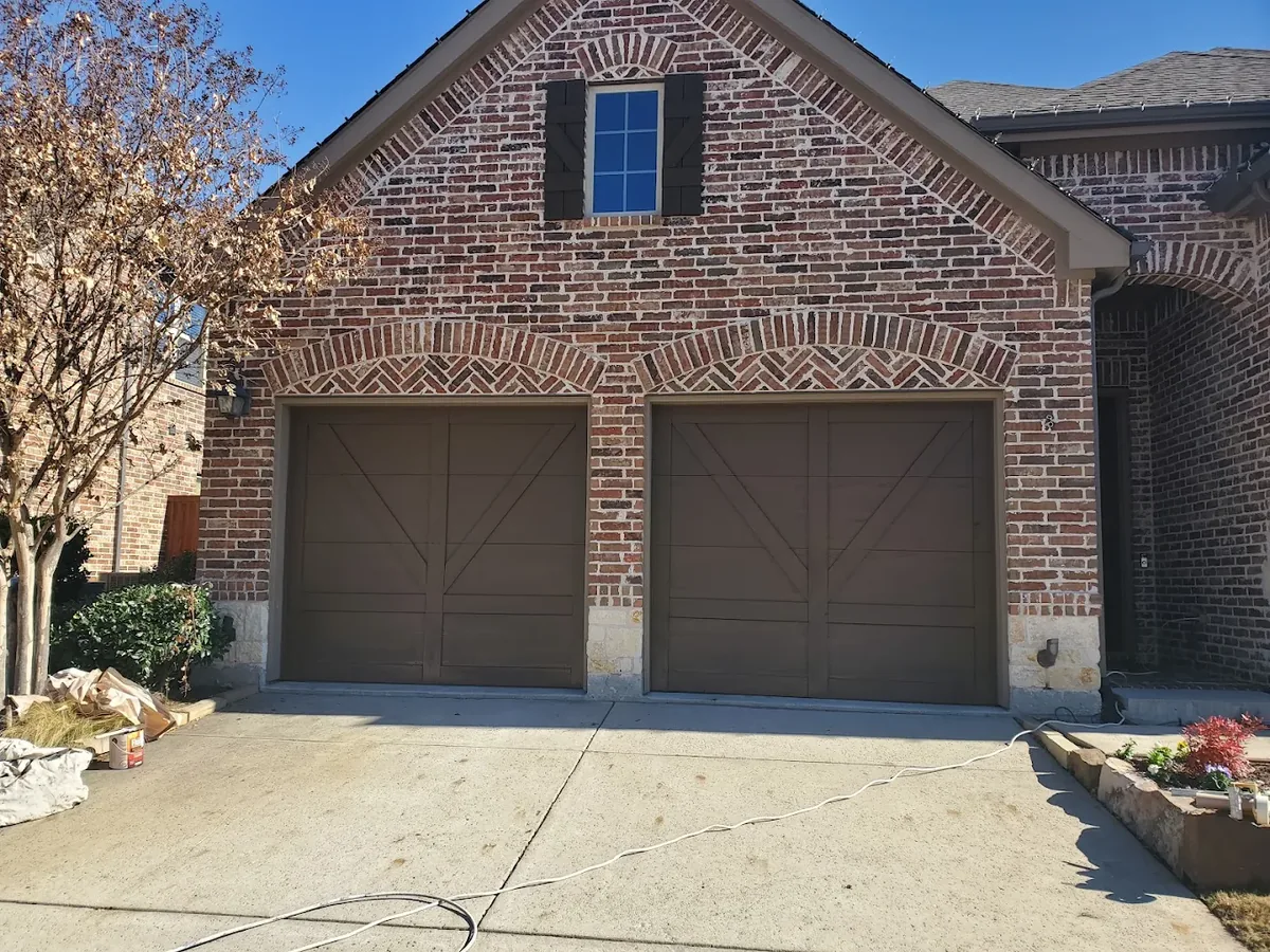 Two brown carriage style garage doors on a brick home