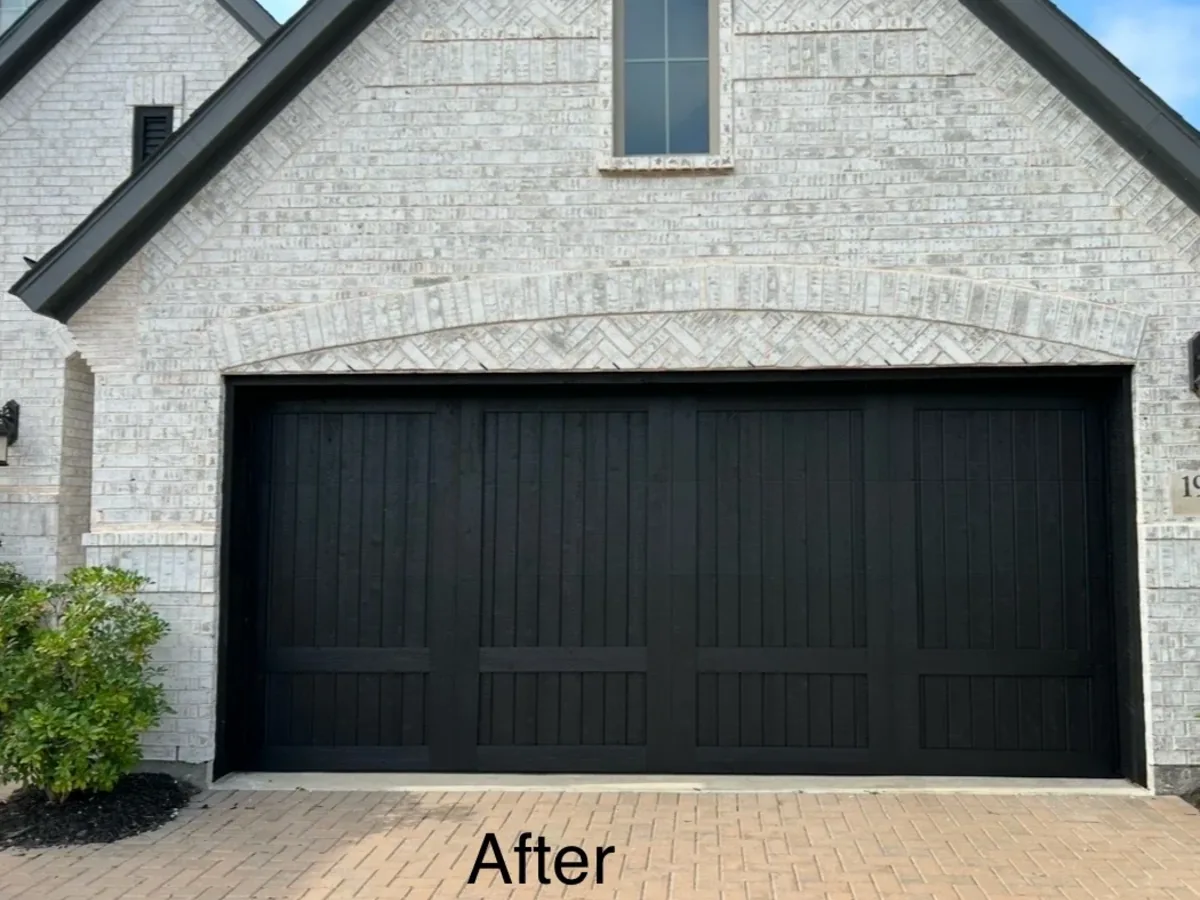Repainted black garage door on a white brick home